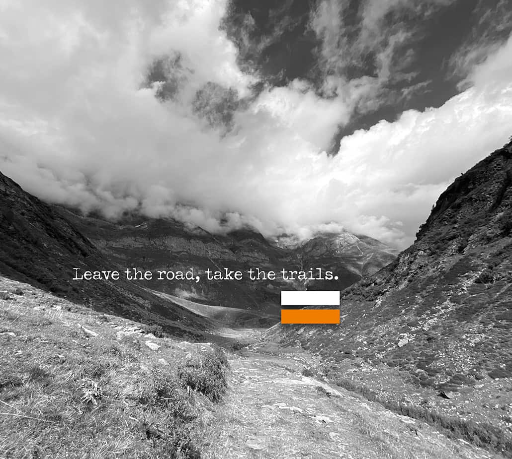 Ein Pfad in den Bergen mit dem Text:Leave the road, take the trails.